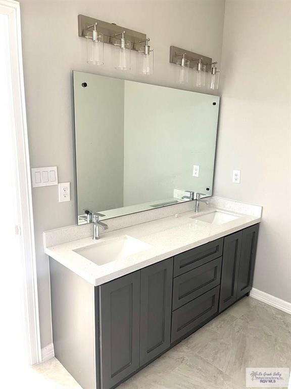 full bath featuring double vanity, a sink, and baseboards