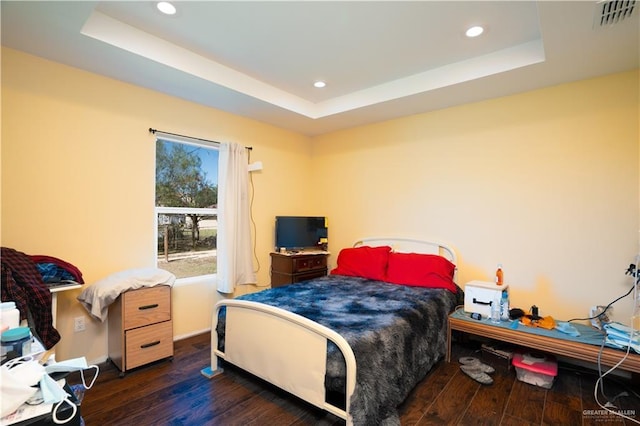 bedroom featuring a tray ceiling and dark wood-type flooring