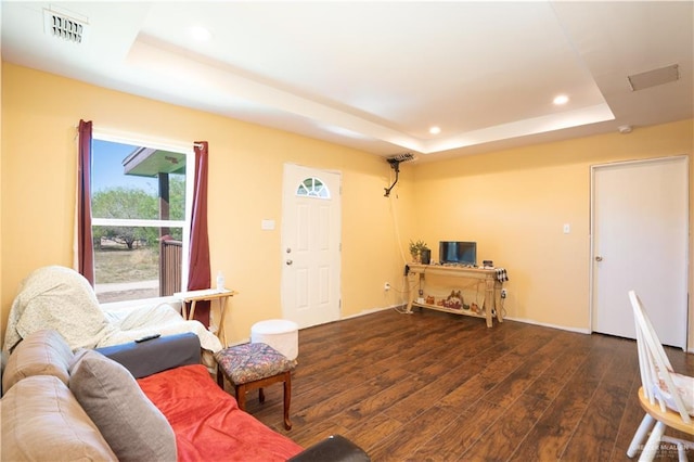 living room featuring dark hardwood / wood-style floors and a raised ceiling