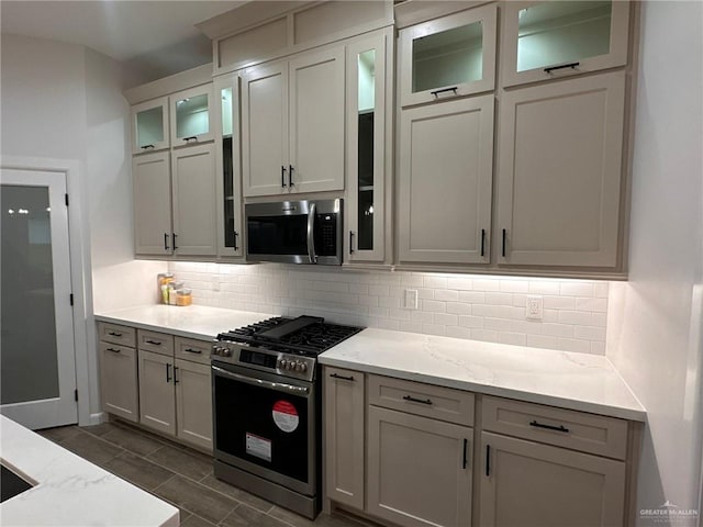 kitchen featuring white cabinetry, decorative backsplash, light stone countertops, and stainless steel appliances