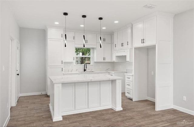 kitchen featuring a center island, white cabinets, and hanging light fixtures