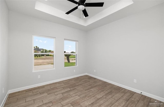 empty room featuring a raised ceiling and ceiling fan