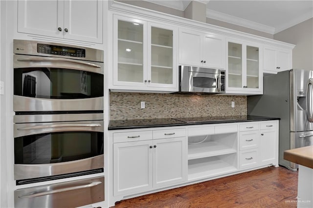 kitchen with white cabinetry, ornamental molding, appliances with stainless steel finishes, dark hardwood / wood-style floors, and backsplash