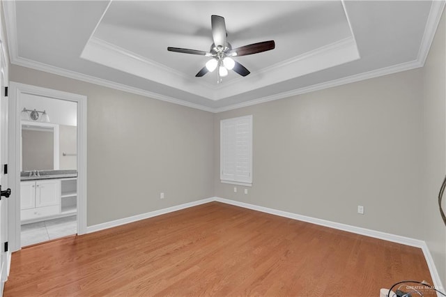 unfurnished bedroom with crown molding, ceiling fan, wood-type flooring, and a tray ceiling