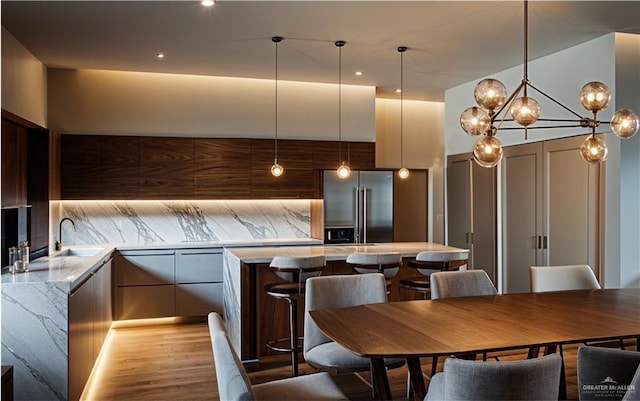 kitchen featuring pendant lighting, light hardwood / wood-style flooring, stainless steel refrigerator, and a notable chandelier