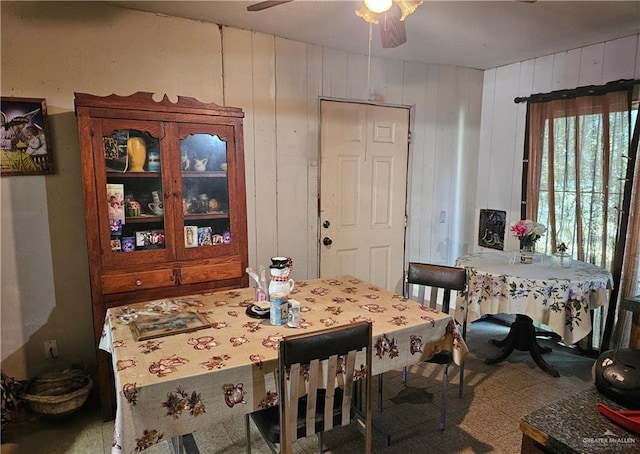 dining room with ceiling fan and wooden walls