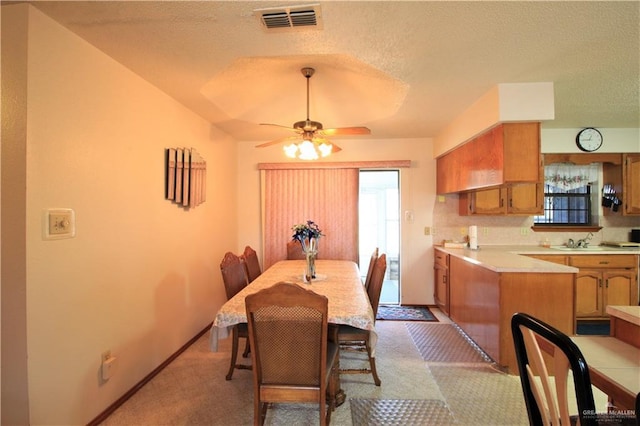 dining area featuring ceiling fan, sink, and a textured ceiling