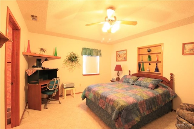 carpeted bedroom featuring a raised ceiling and ceiling fan