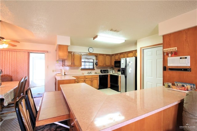 kitchen featuring ceiling fan, kitchen peninsula, a textured ceiling, and black appliances