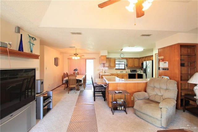 living room with ceiling fan, light carpet, and a textured ceiling