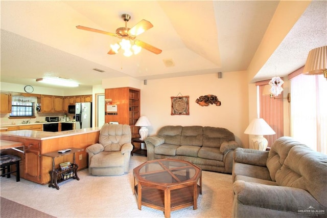 living room with ceiling fan, light colored carpet, and a tray ceiling