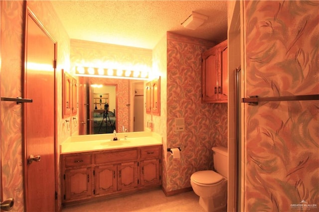 bathroom with vanity, a textured ceiling, and toilet