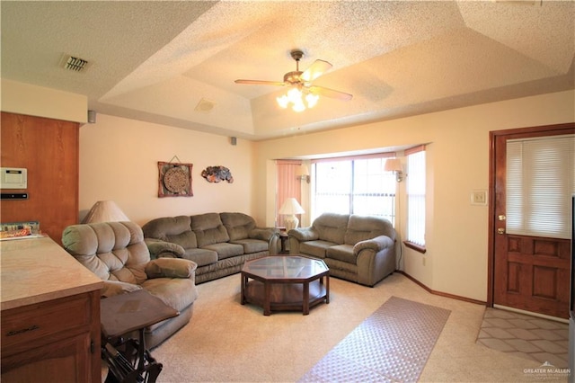 carpeted living room featuring a raised ceiling, ceiling fan, and a textured ceiling