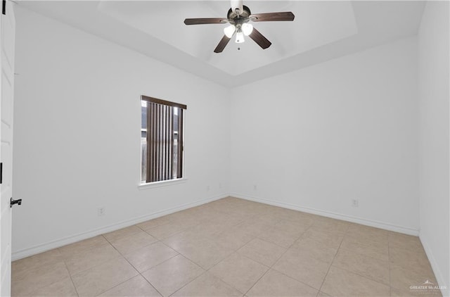 tiled spare room featuring ceiling fan and a raised ceiling