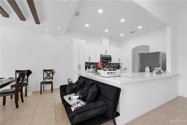 kitchen featuring light tile patterned flooring, appliances with stainless steel finishes, white cabinets, backsplash, and kitchen peninsula