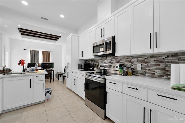 kitchen featuring light tile patterned flooring, appliances with stainless steel finishes, white cabinets, and backsplash