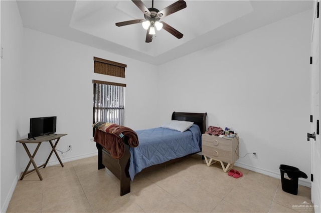 bedroom featuring light tile patterned flooring, ceiling fan, and a tray ceiling