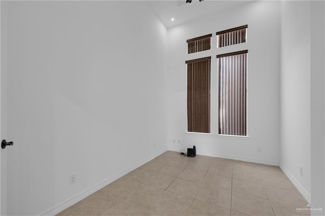 tiled empty room featuring a high ceiling