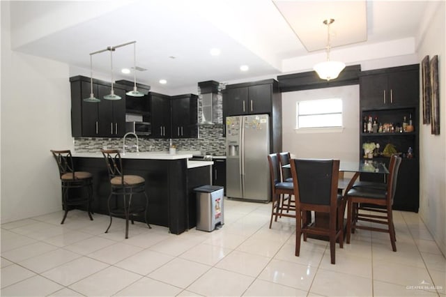314 N 17th St, Hidalgo, TX 78557 - kitchen with stainless steel appliances, dark cabinetry, a peninsula, light countertops, and tasteful backsplash