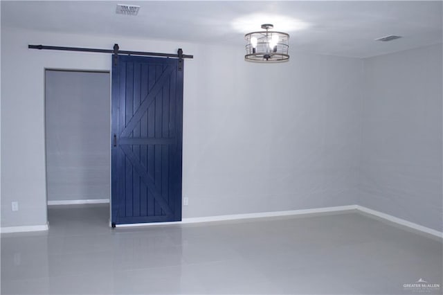 tiled spare room featuring a barn door and a chandelier