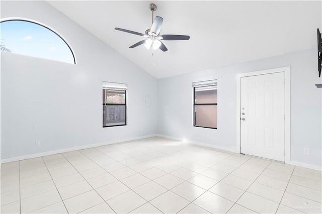 spare room featuring vaulted ceiling, light tile patterned floors, a ceiling fan, and baseboards