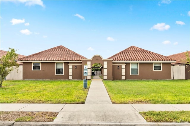 view of front facade featuring a tile roof, a front lawn, and stucco siding