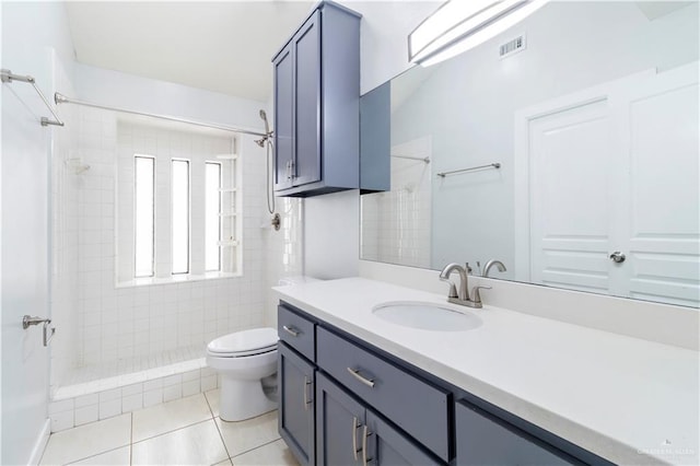 full bathroom featuring tile patterned flooring, visible vents, toilet, a tile shower, and vanity