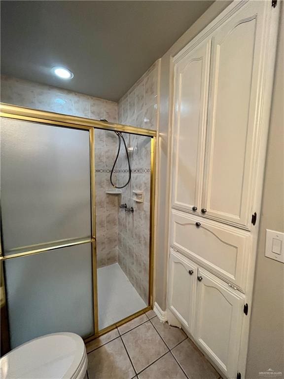 bathroom with toilet, tile patterned floors, and a shower with door