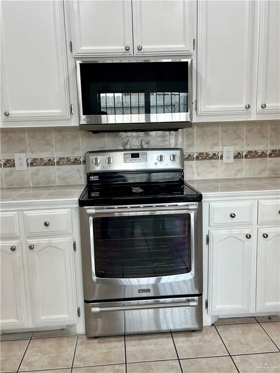 kitchen with white cabinetry, stainless steel appliances, and tasteful backsplash