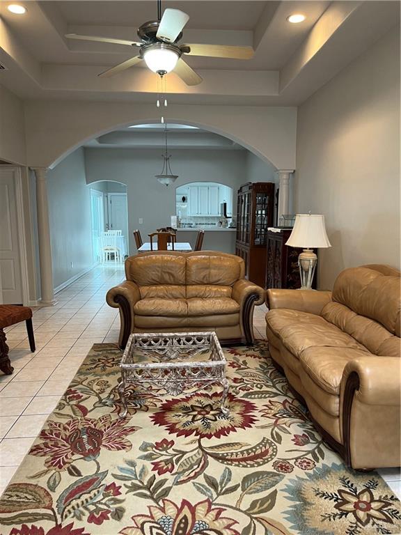 tiled living room featuring a tray ceiling and ceiling fan