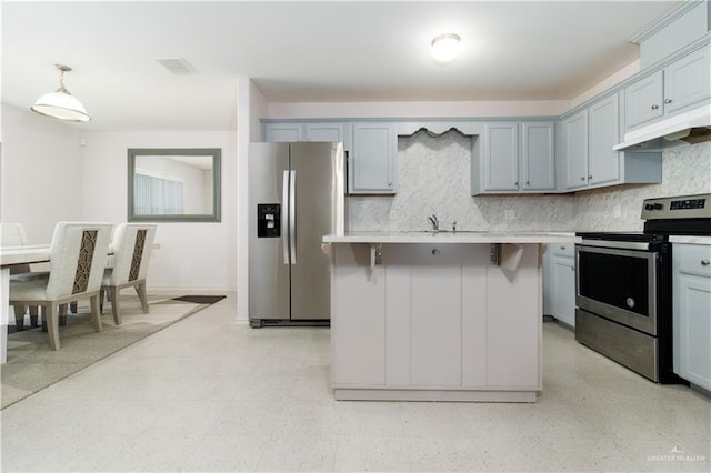 kitchen with appliances with stainless steel finishes, a breakfast bar, backsplash, and decorative light fixtures