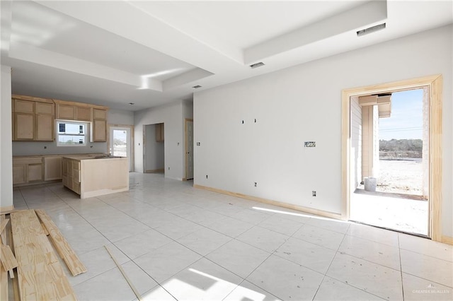 unfurnished living room featuring a raised ceiling and light tile patterned floors