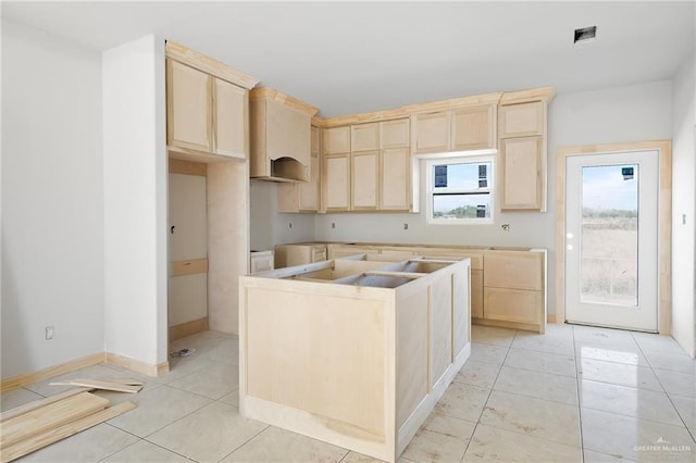 kitchen featuring light brown cabinetry, a kitchen island, and light tile patterned flooring