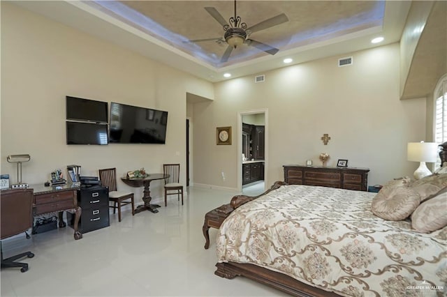 bedroom featuring a tray ceiling, ceiling fan, and ensuite bathroom