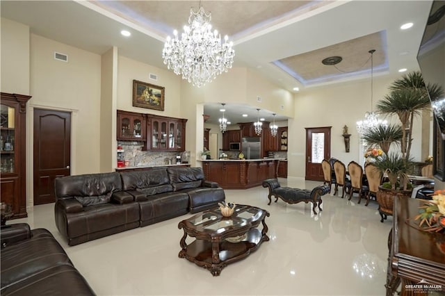 living room with a chandelier, a high ceiling, and a tray ceiling