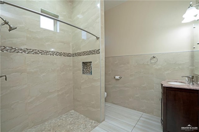 bathroom with vanity, tiled shower, and tile walls