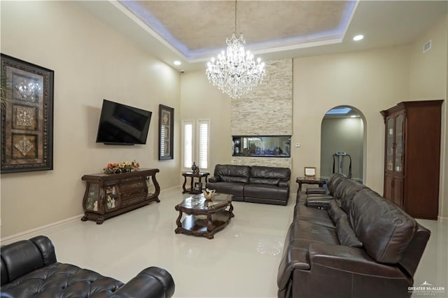 living room featuring a chandelier, a high ceiling, and a tray ceiling