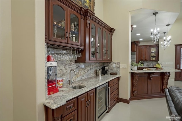 bar featuring decorative backsplash, light stone counters, beverage cooler, sink, and pendant lighting