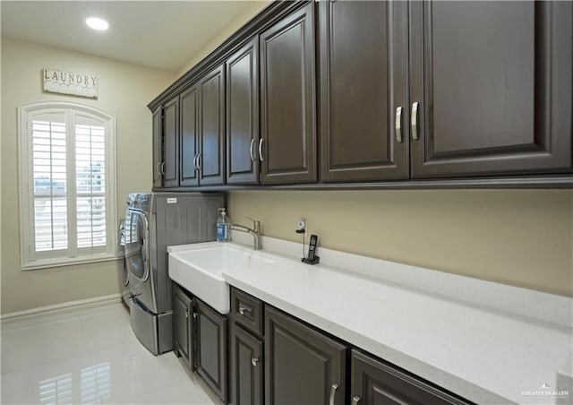 laundry room with cabinets, washing machine and dryer, light tile patterned flooring, and sink