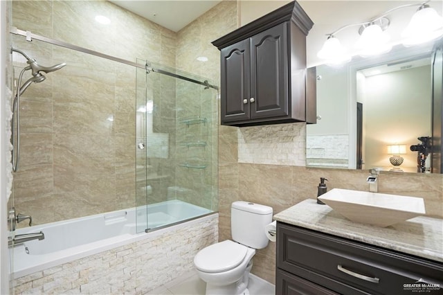 full bathroom with shower / bath combination with glass door, vanity, and tile walls