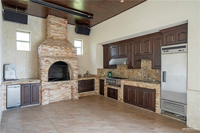 kitchen with dark brown cabinetry, built in fridge, sink, and stainless steel cooktop