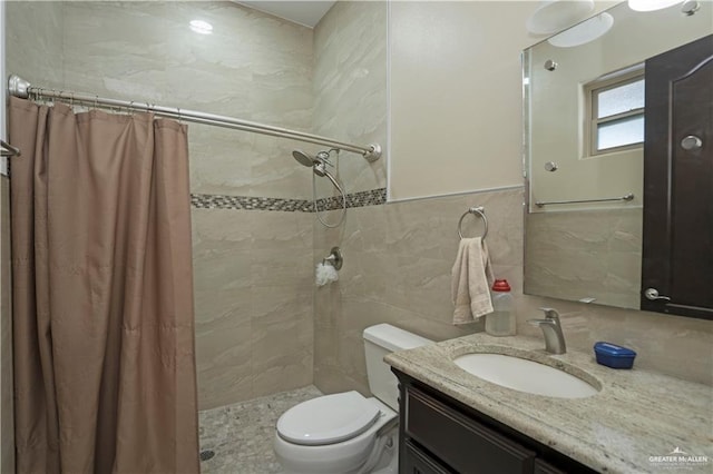 bathroom with vanity, toilet, tile walls, and walk in shower