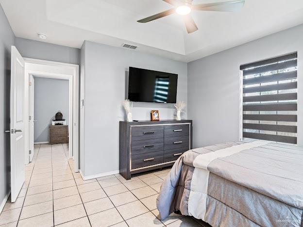 bedroom with visible vents, baseboards, light tile patterned floors, and a tray ceiling