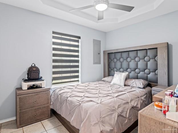 bedroom with baseboards, electric panel, a tray ceiling, a ceiling fan, and light tile patterned floors