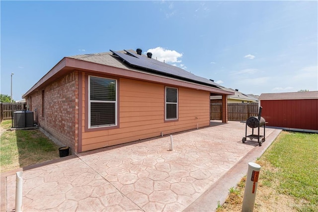 back of property with an outbuilding, brick siding, a patio, central AC unit, and a fenced backyard