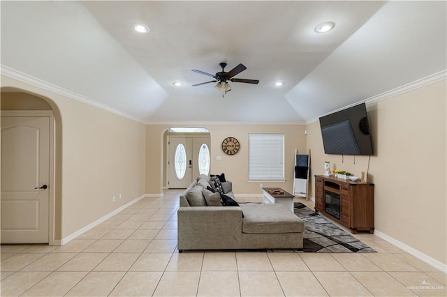 living area with arched walkways, light tile patterned flooring, a ceiling fan, baseboards, and vaulted ceiling