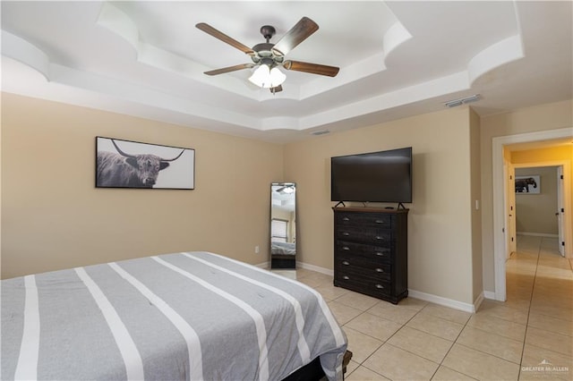 bedroom with light tile patterned floors, a ceiling fan, visible vents, baseboards, and a raised ceiling