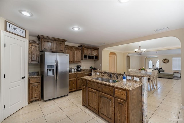 kitchen featuring light tile patterned floors, arched walkways, a sink, and stainless steel fridge with ice dispenser