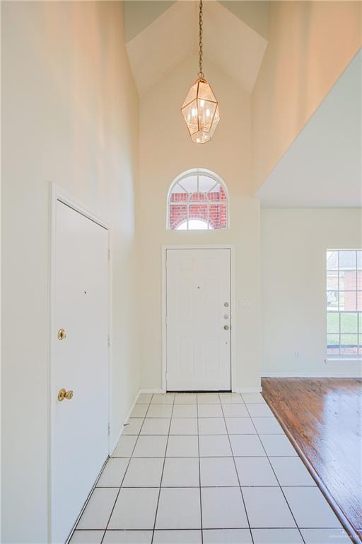 4612 Laurel Ave, Mcallen, TX 78501 - entryway with high vaulted ceiling, a chandelier, light tile patterned flooring, and baseboards