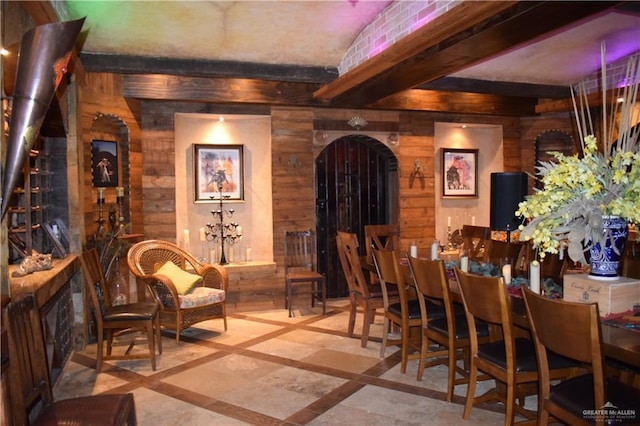 wine cellar with beamed ceiling, arched walkways, and wood walls